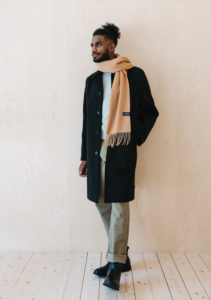 TBCo Men's Lambswool Scarf in Camel styled with black winter coat and light trousers, showcasing fringed design and classic drape