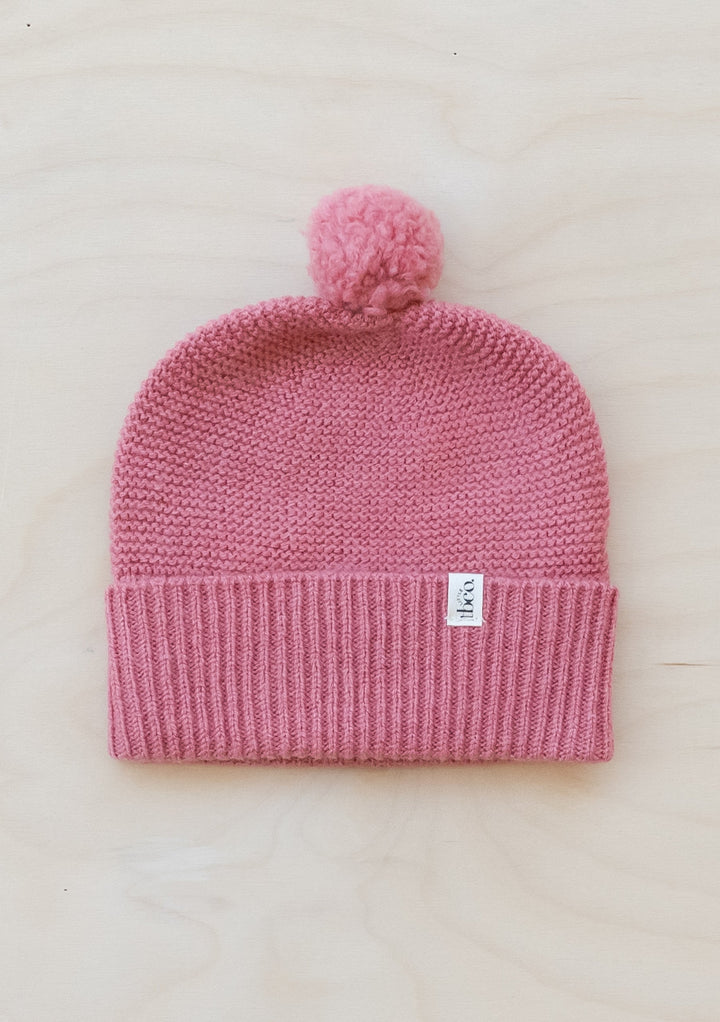 TBCo Merino Wool Baby Beanie in Rose with pom pom detail, featuring ribbed cuff and knitted texture in soft pink colour
