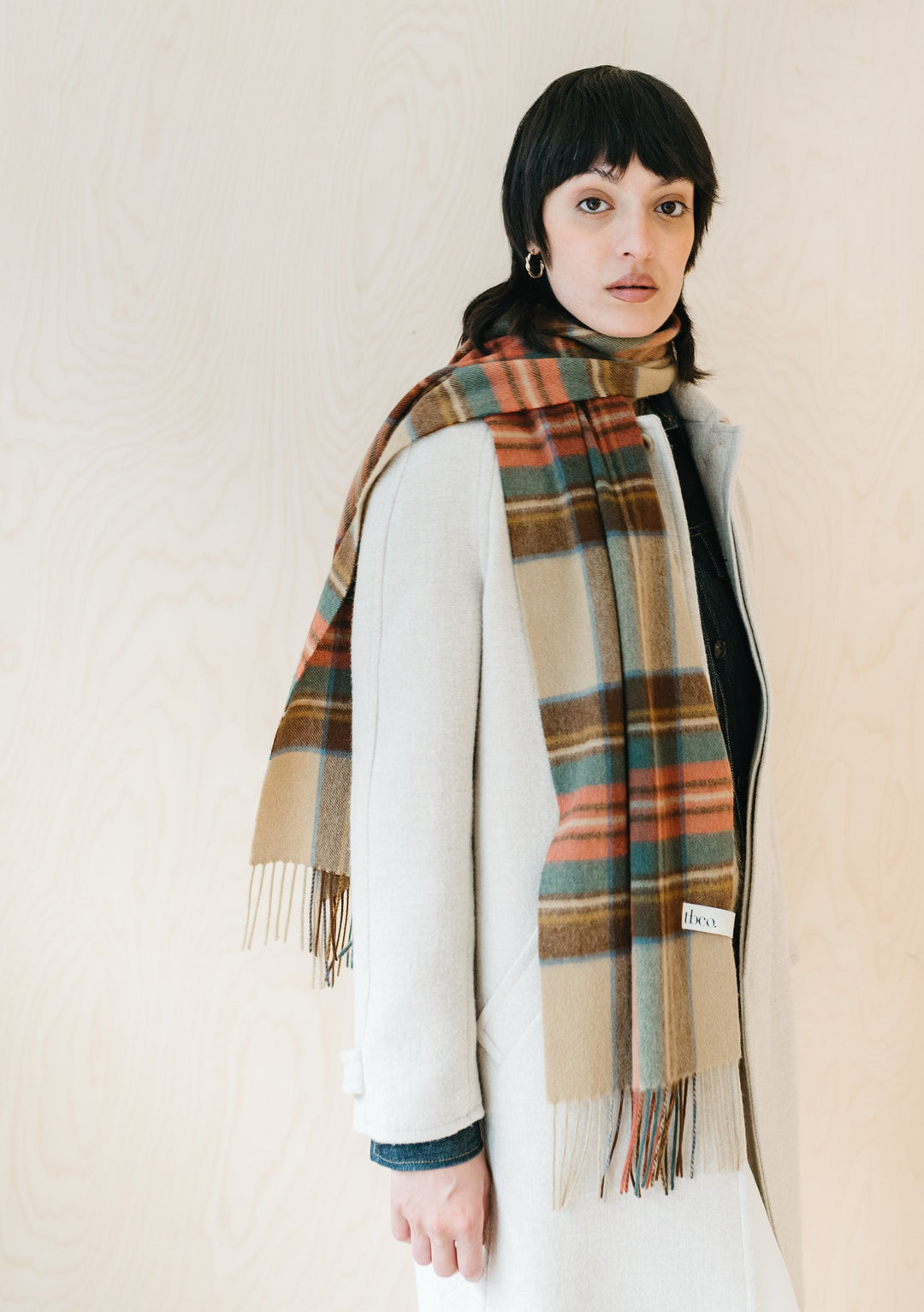 TBCo Stewart Dress Antique Tartan cashmere scarf with fringe, styled draped over white winter coat showing plaid pattern