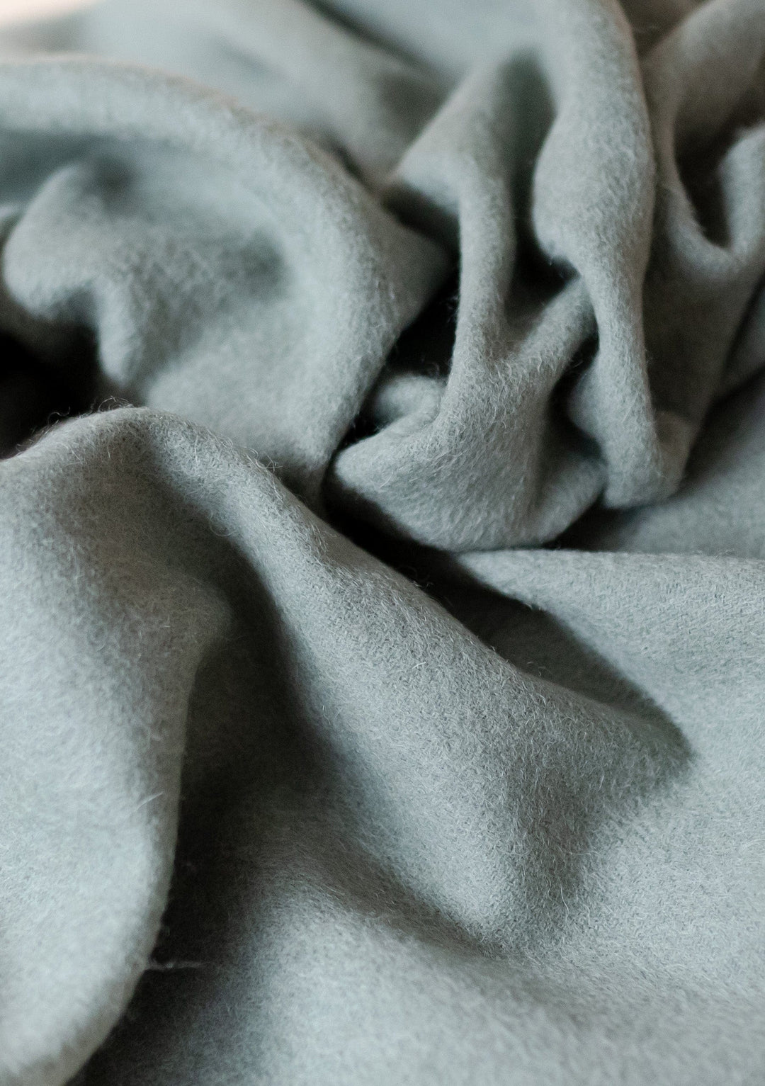 TBCo Lambswool Small Blanket in Sage Melange showing soft textured folds and gentle draping of premium wool fabric