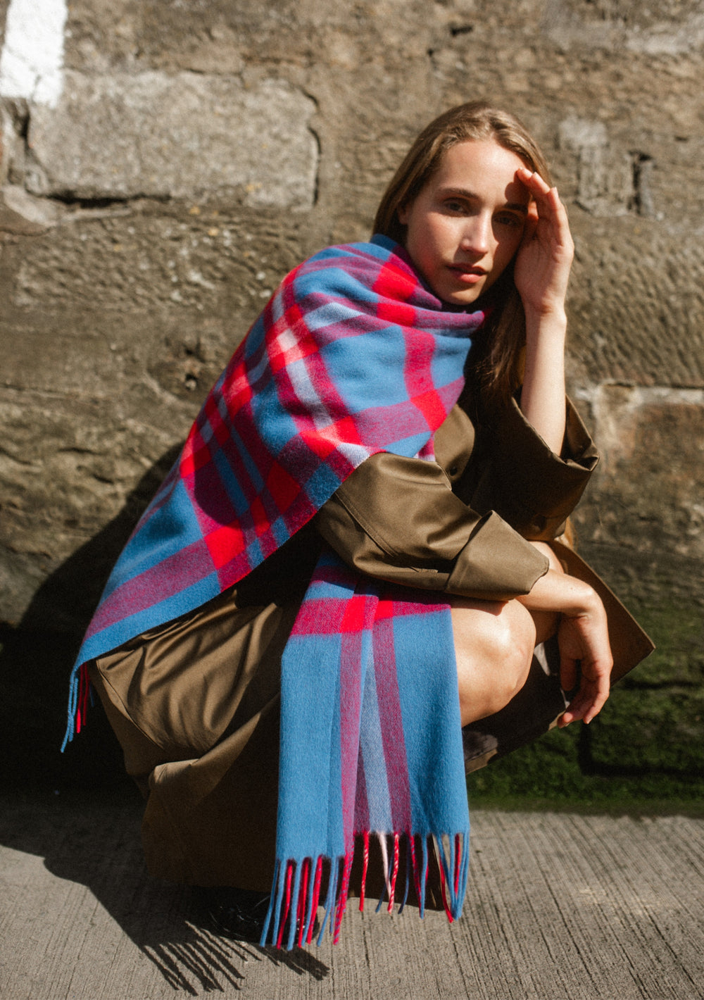 Woman wearing a Lambswool Oversized Scarf in Blue Modern Tartan by TBCo draped over a trench coat outdoors