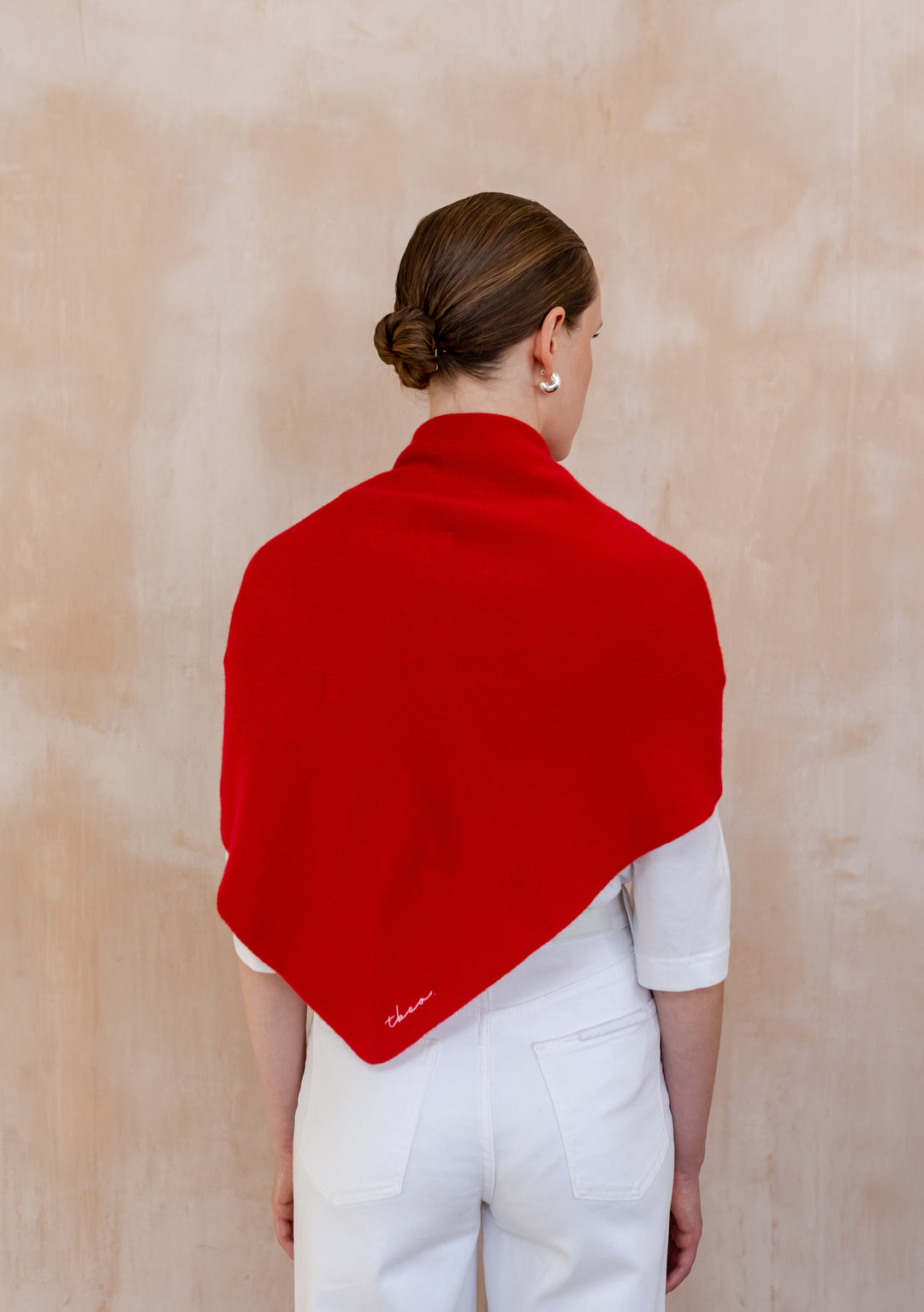 Woman seen from behind wearing a Large Merino Triangle Scarf in Red by TBCo over a white outfit