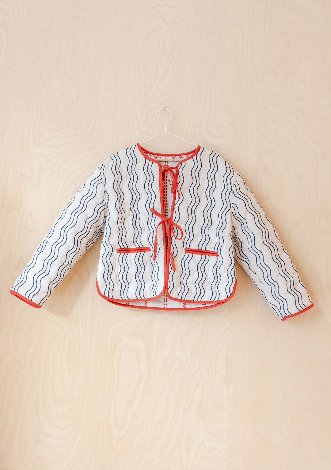 TBCo Quilted Cotton Jacket in Reversible Flora Wave with navy wave pattern and orange trim on cream background