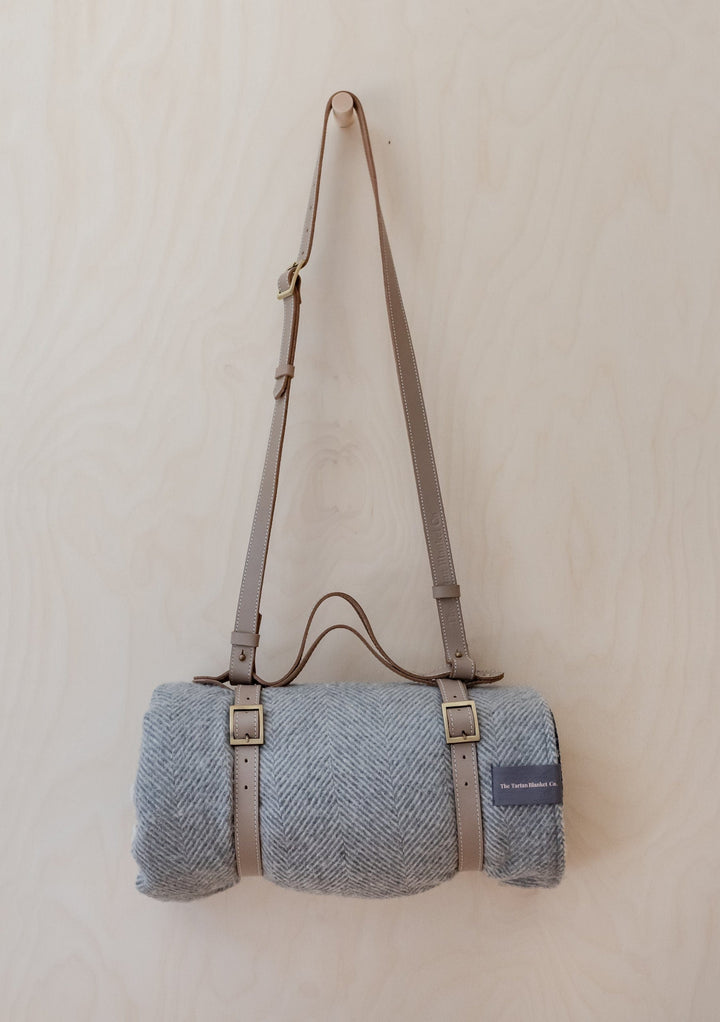 TBCo Leather Picnic Carrier with adjustable shoulder strap and brass buckles, shown with grey wool blanket rolled inside