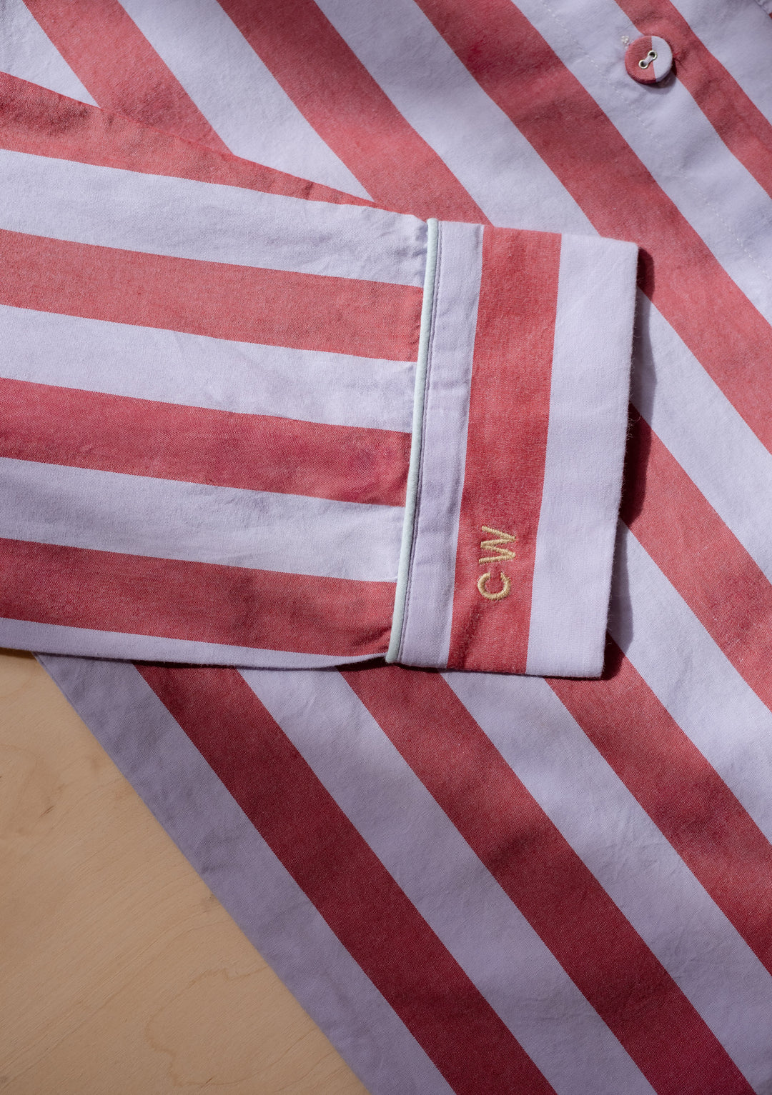 Close-up of striped sleeve with embroidery on the cuff from TBCo Cotton Pyjamas in Camel Harlequin detailing