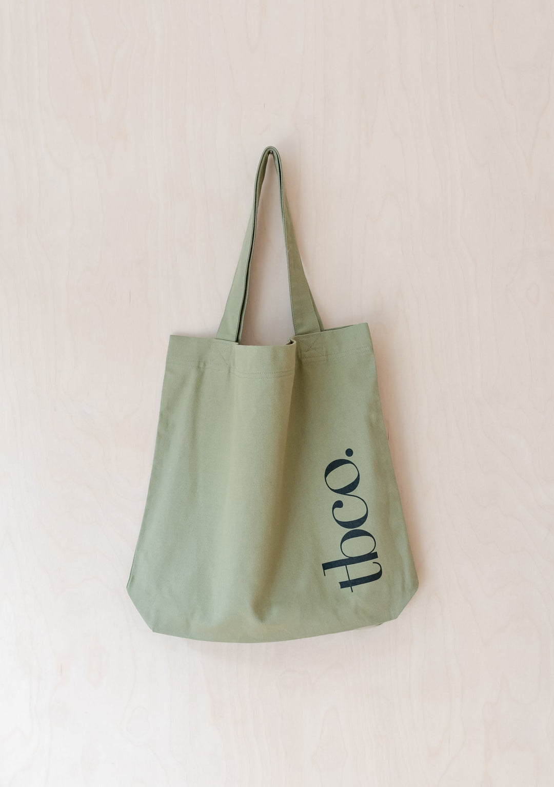 TBCo Recycled Cotton Tote in Olive featuring long handles and minimalist black logo design on pale green canvas material