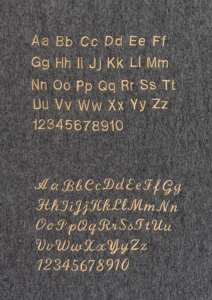 Gold alphabet and numbers displayed in two fonts on grey background, showcasing TBCo's typographic styles