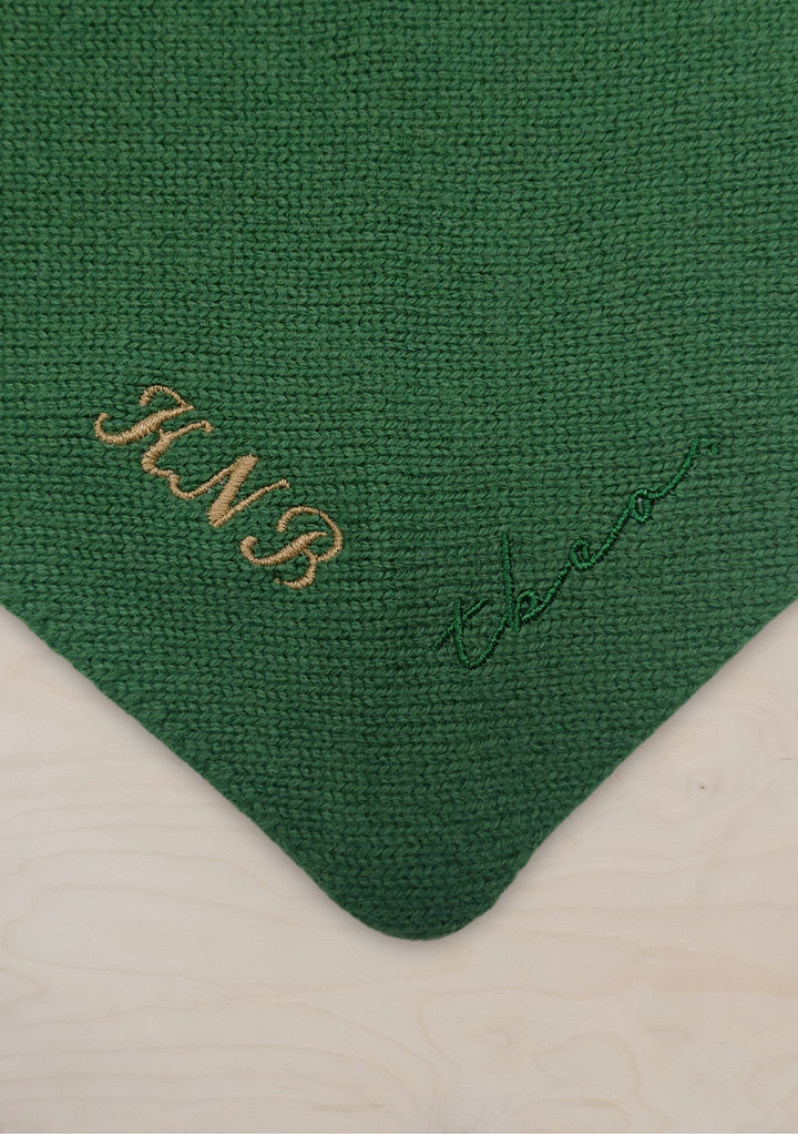 Close-up of the embroidered corner on the Large Merino Triangle Scarf in Pink Stripe by TBCo showing custom initials and logo on green wool.