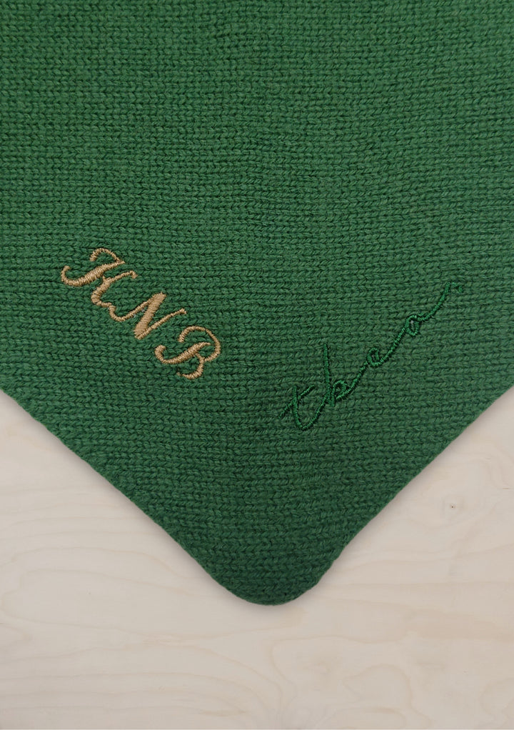 Close-up detail of TBCo Merino Triangle Scarf in coffee brown showing knitted texture and embroidered personalisation on green fabric