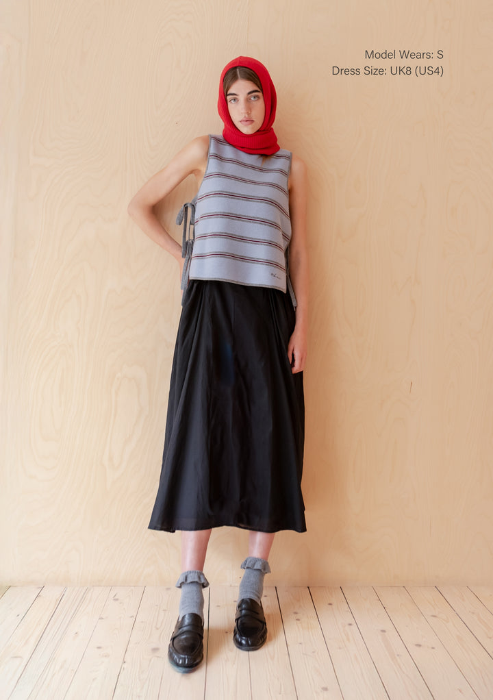 Model wearing TBCo Merino Wool Tie Vest in Blue Stripe with side tie closures styled with black skirt and red headscarf