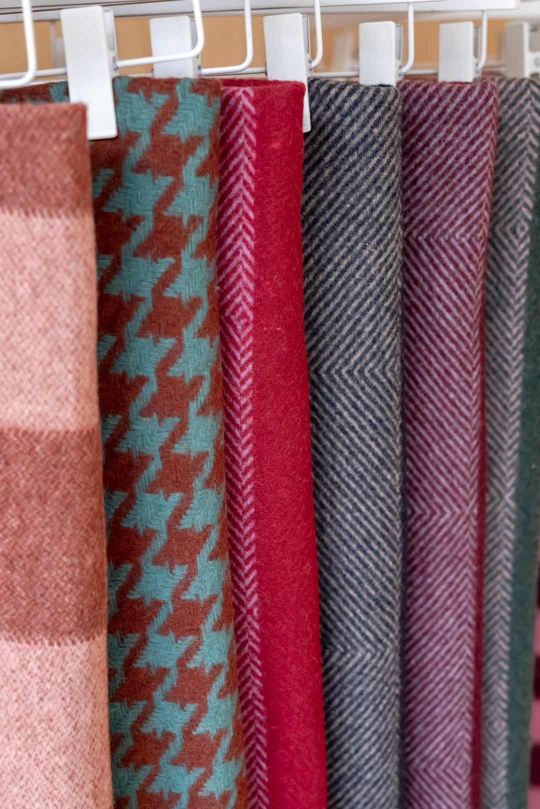 Sample Sale Recycled Wool Blanket in Pink Diamond Stripe by TBCo hanging with other patterned blankets in soft colours