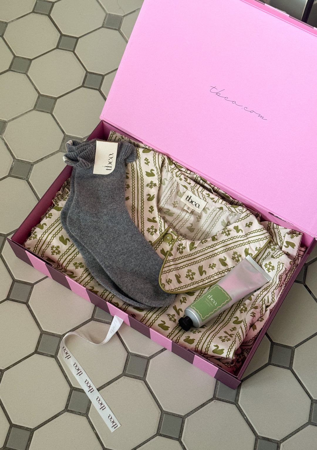 TBCo Mother's Day Gift Box with a Pink gift box including baby cotton pyjamas and socks on a tiled floor