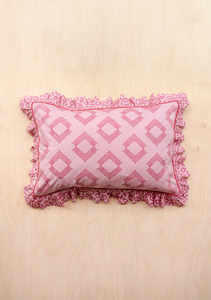 Pair of Cotton Pillowcases in Pink Diamond by TBCo featuring geometric pink shapes and ruffled edges on pale wood background