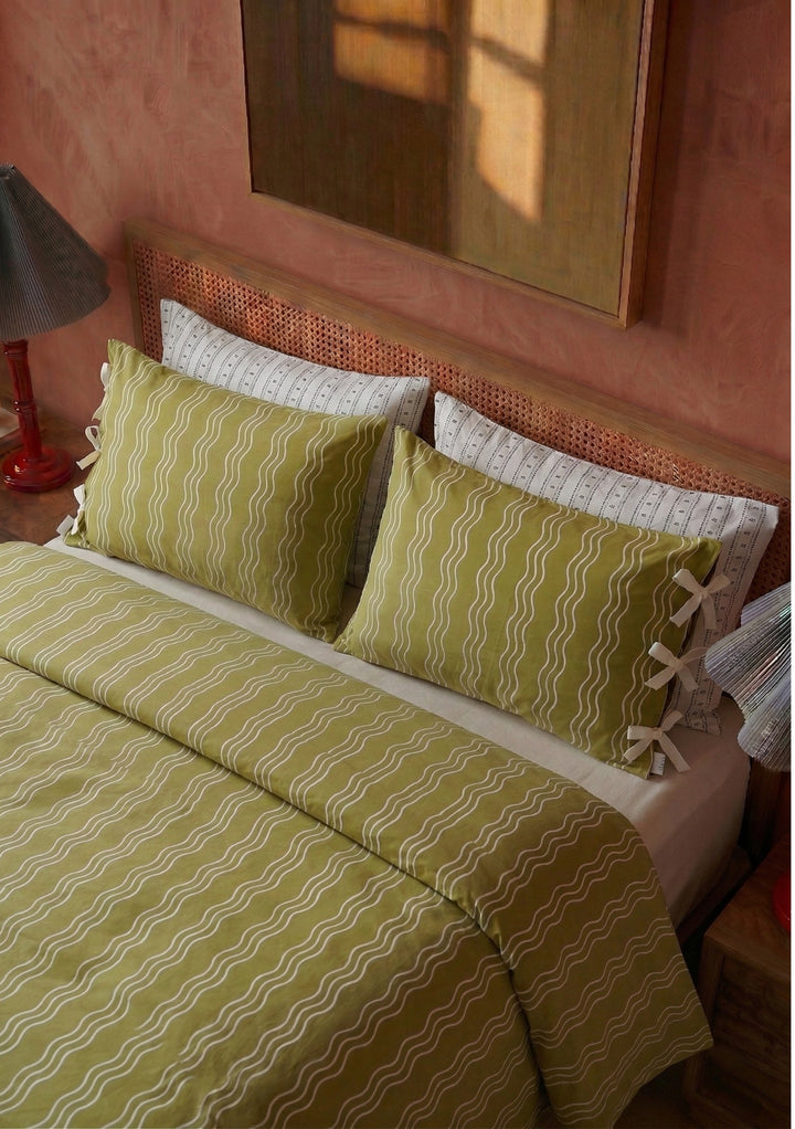 Pair of Cotton Pillowcases in Olive Wave by TBCo with wavy stripes and bow details on a styled bed setting