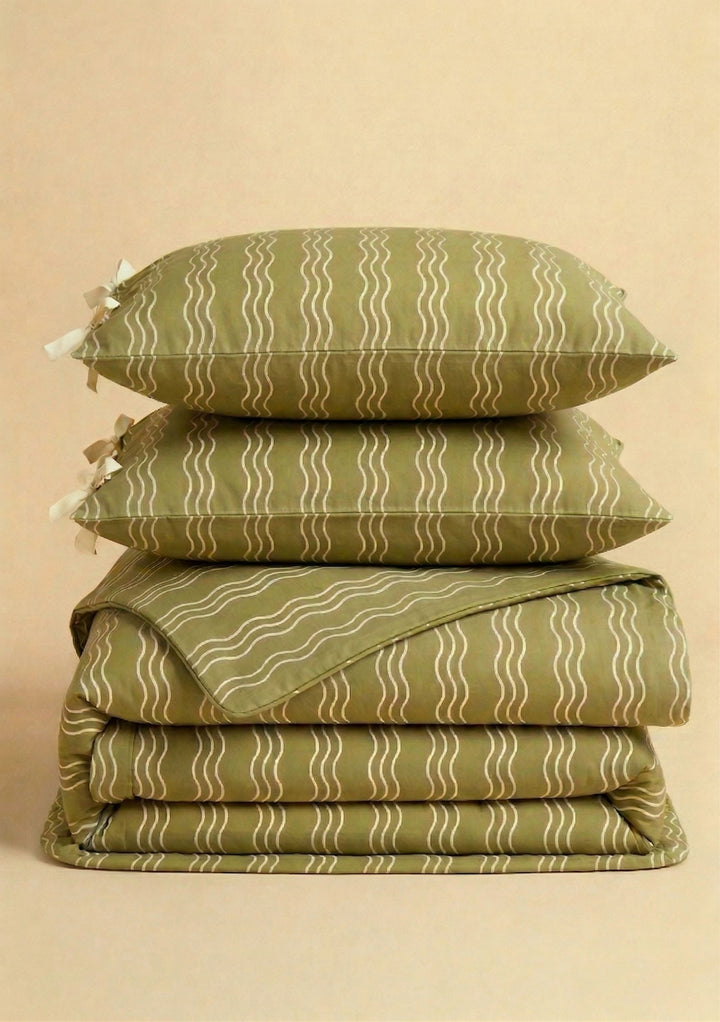 Pair of Cotton Pillowcases in Olive Wave by TBCo stacked on folded matching cotton bedding with subtle wave pattern