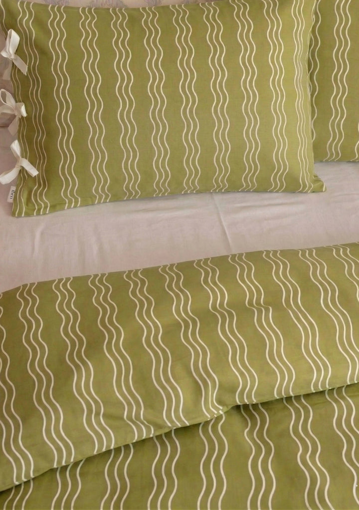 Cotton Duvet Cover in Olive Wave by TBCo featuring white wavy stripes on olive green cotton fabric in a bedding setting