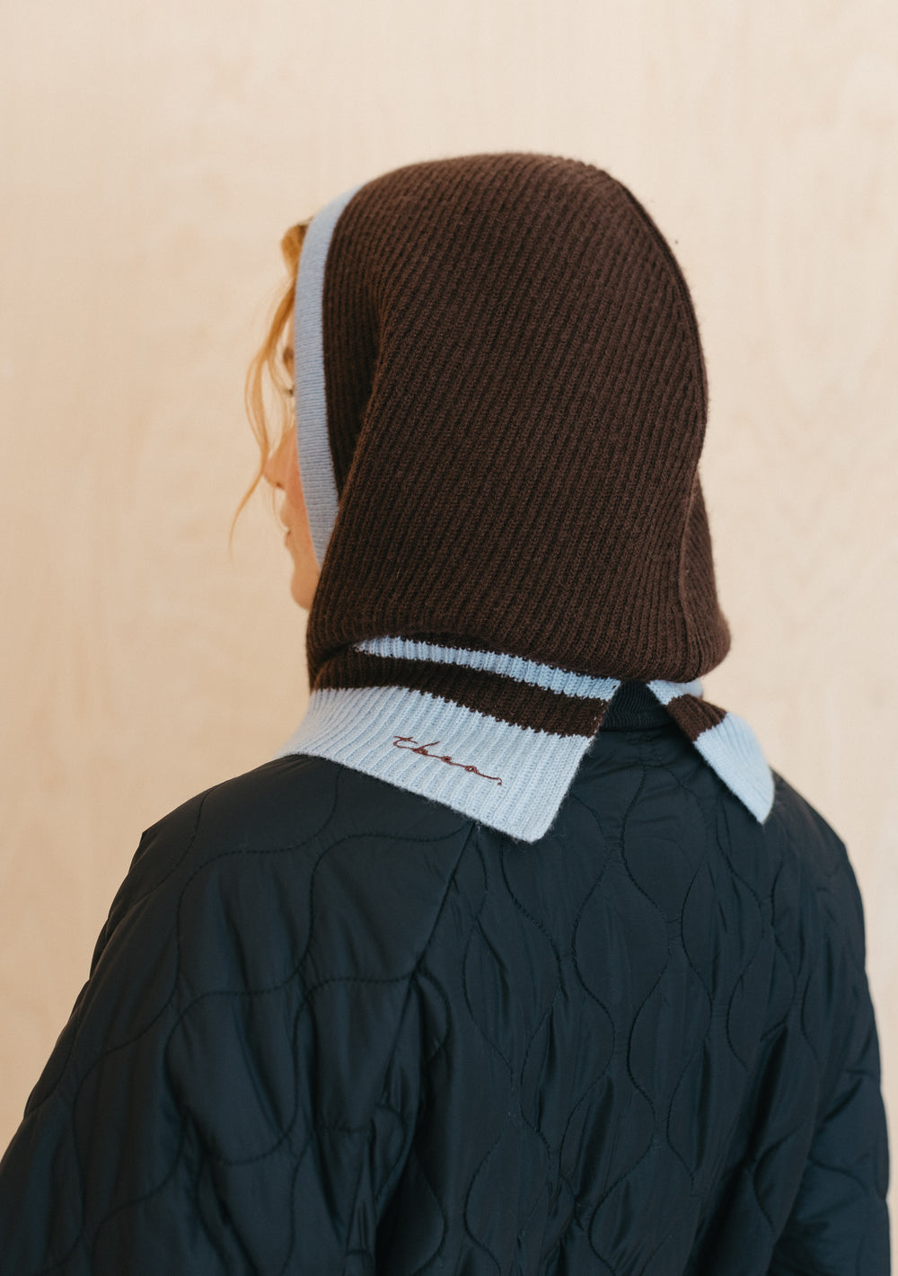 TBCo Merino Hood in Brown and Blue with ice blue trim, shown from back view on model wearing dark quilted jacket