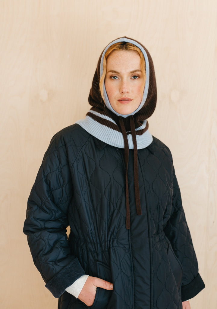 TBCo Merino Hood in Brown with ice blue trim shown with quilted winter coat, displaying hood's snug fit and versatile style