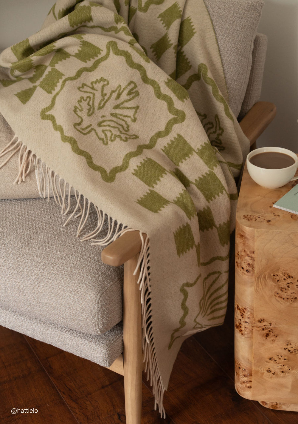 TBCo Lambswool Blanket in Green Motif draped over chair with delicate fringes and natural leaf pattern in soft green tones