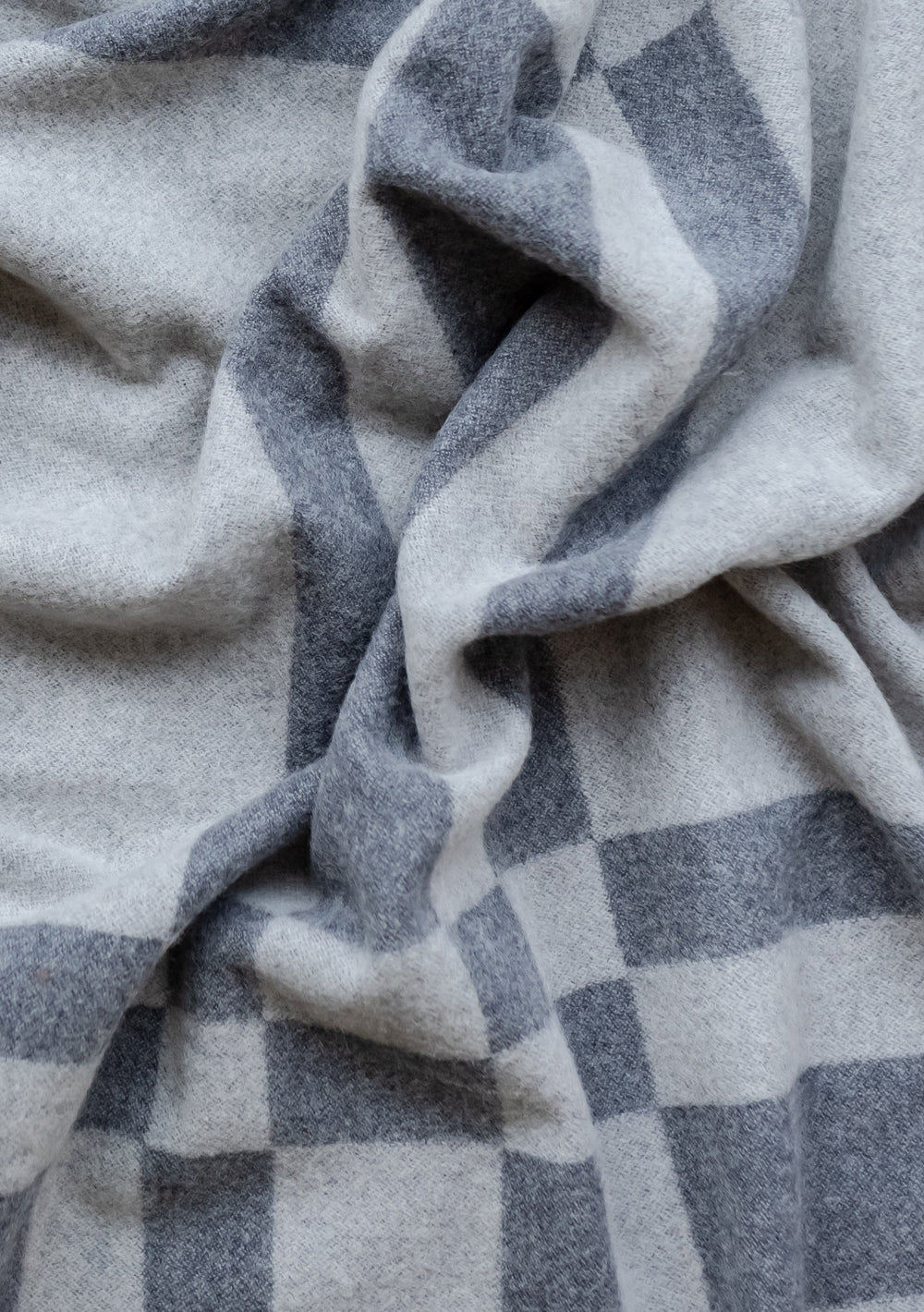 TBCo Lambswool Blanket in Grey Pillar Check featuring soft draping folds showing textured checkered pattern in light and dark grey