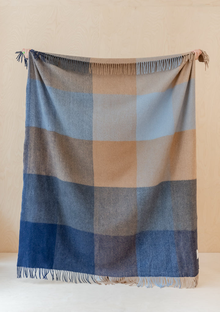TBCo Recycled Wool Blanket in blue herringbone block check pattern displayed with fringe detail against neutral wall