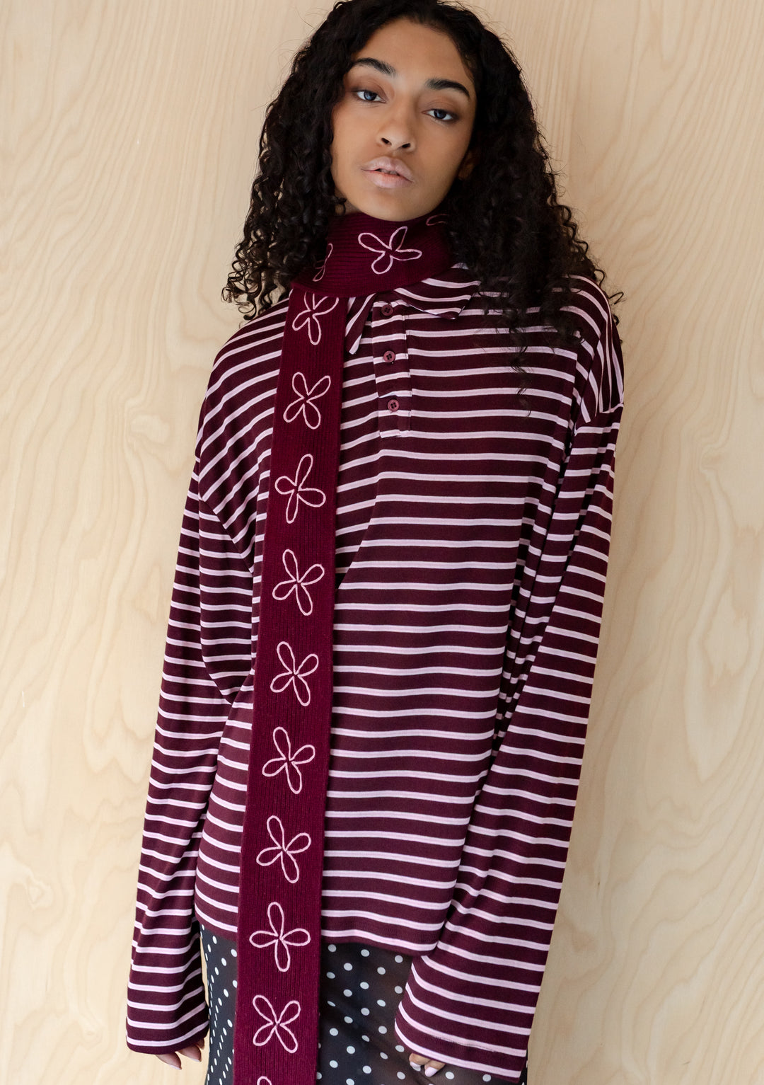 Model wearing TBCo Merino Wool Skinny Scarf in Burgundy Flora with pale pink floral embroidery and striped top