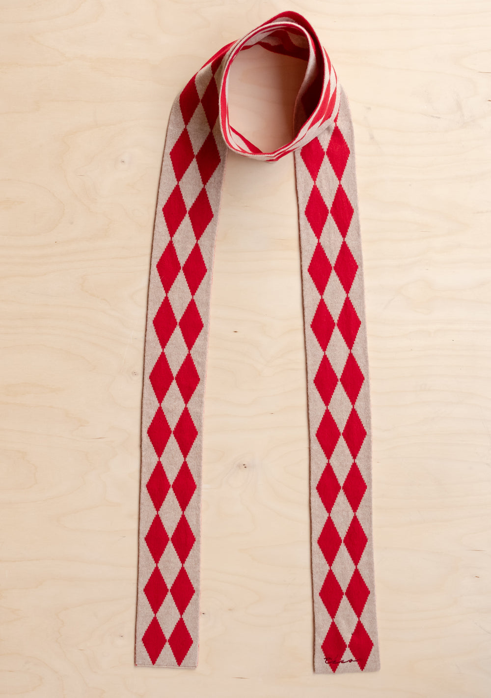 TBCo Merino Wool Skinny Scarf in Red Harlequin with red and oatmeal diamond pattern laid flat on light wood surface
