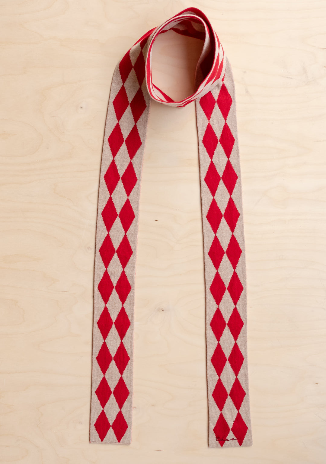 TBCo Merino Wool Skinny Scarf in Red Harlequin with red and oatmeal diamond pattern laid flat on light wood surface