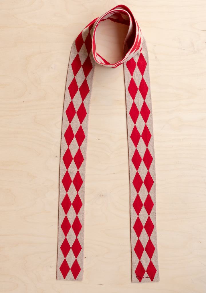 TBCo Merino Wool Skinny Scarf in Red Harlequin with red and oatmeal diamond pattern laid flat on light wood surface