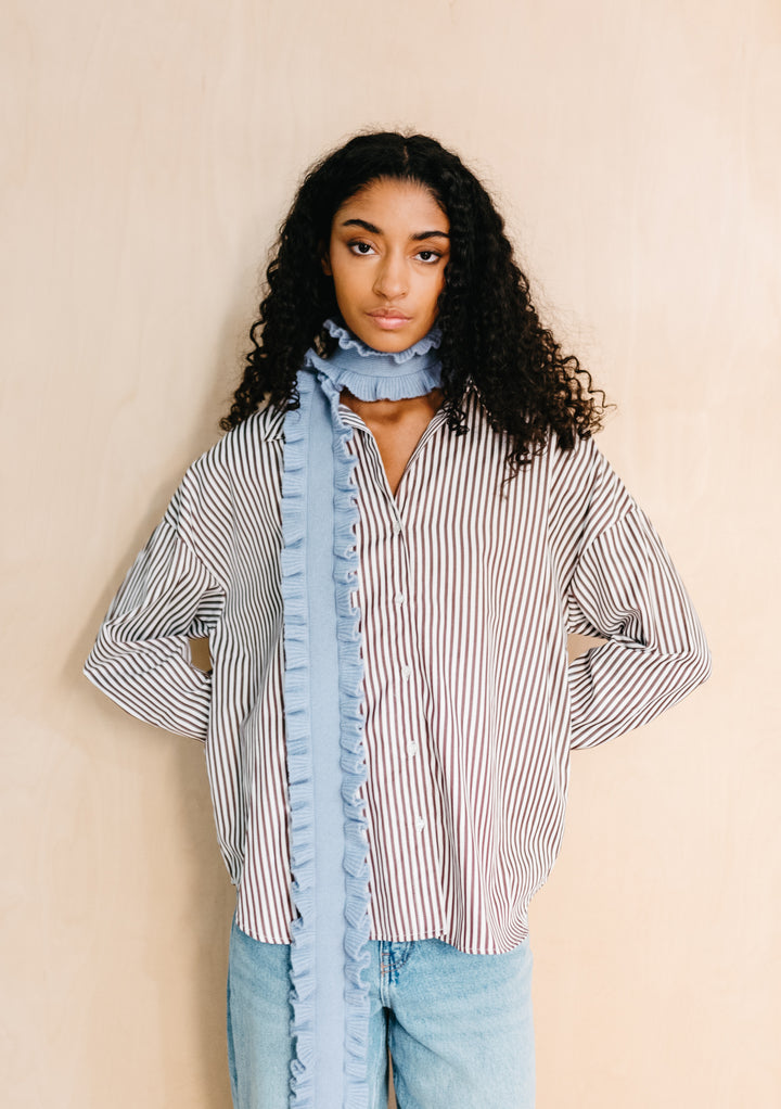 Model wearing TBCo Merino Wool Skinny Scarf in Blue Ruffle with ruffled trim styled over striped shirt and jeans