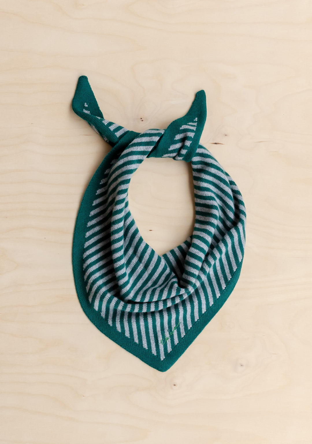 TBCo Merino Wool Triangle Scarf in Green & Charcoal Stripe, showcasing a forest green knit with light-gray stripes, laid flat on a light wood surface.