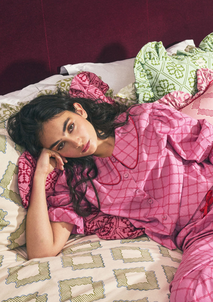 Model reclining on bed wearing TBCo Cropped Cotton Pyjamas in Pink Lattice, gallery position 2, portrait orientation.