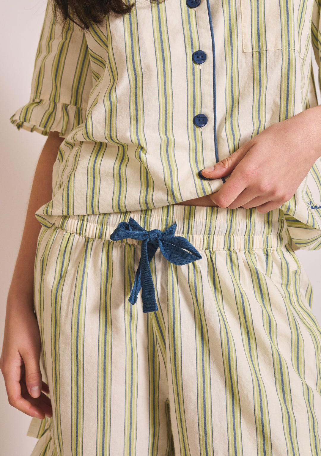 Close-up of TBCo Cotton Pyjamas in Olive Stripe Ruffle showing button detail and blue waist tie in gallery position 5 portrait view