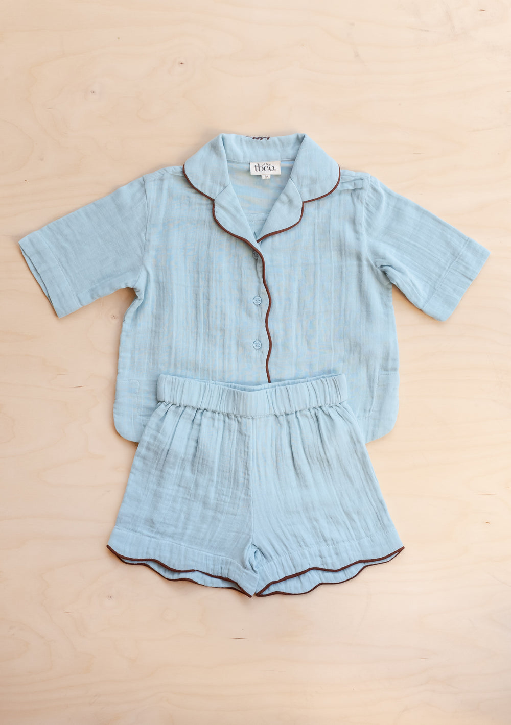 TBCo Cotton Kids Pyjamas in Blue with short sleeves, scalloped trim, and elasticated shorts on neutral backdrop