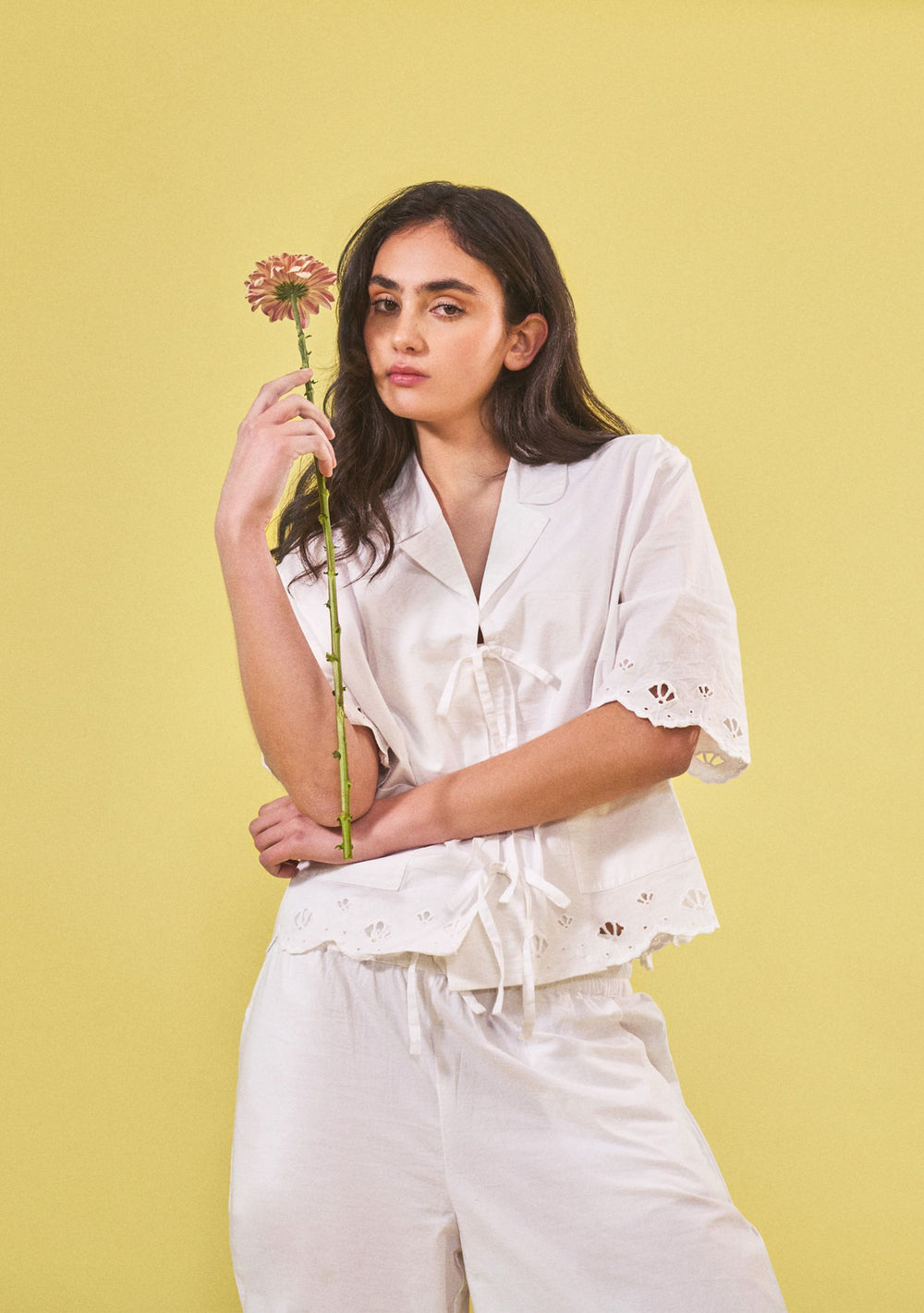 Model wearing TBCo Cropped Cotton Pyjamas in White Shell with broderie embroidery, holding a flower, gallery image 2 portrait