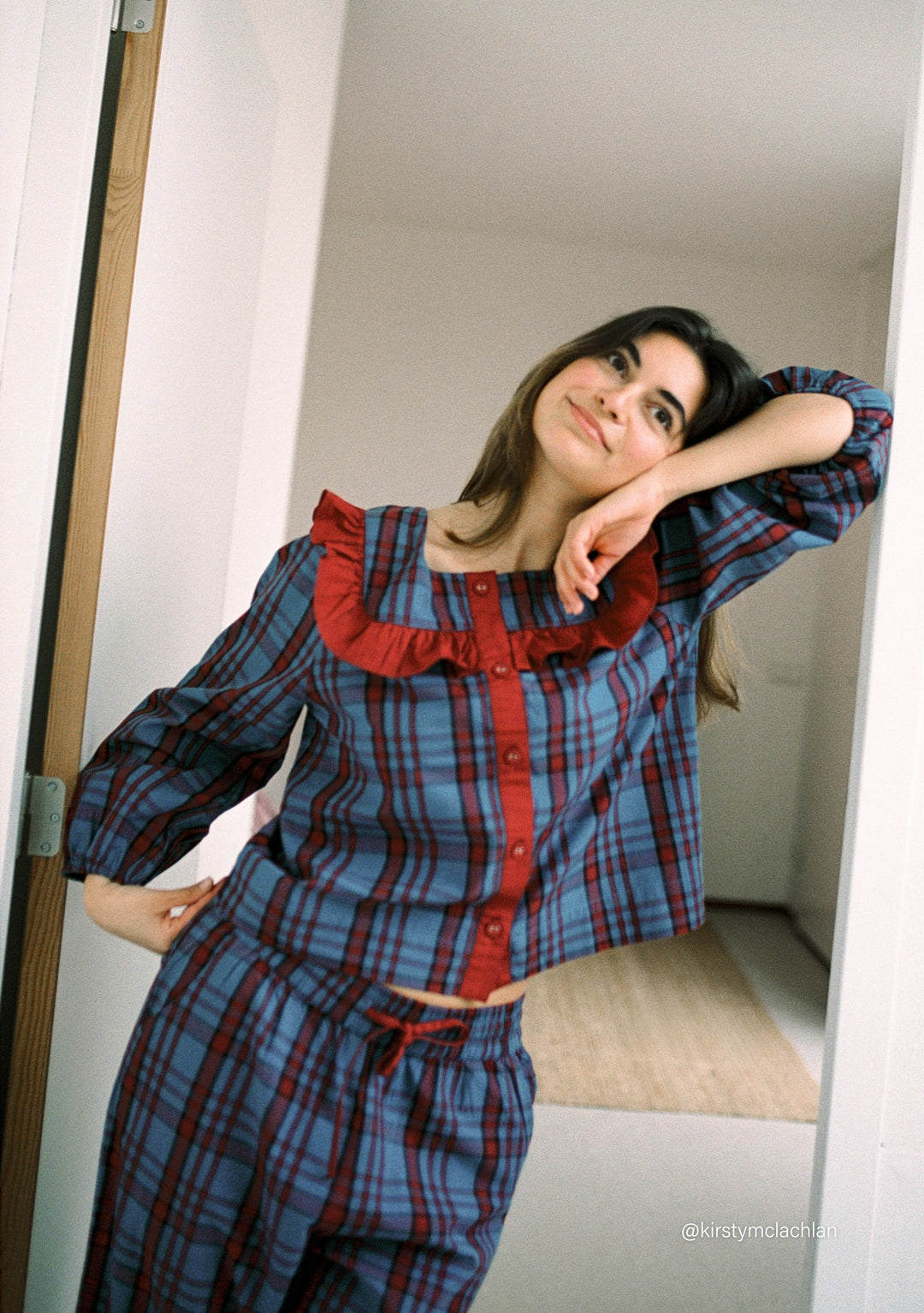 Woman in a relaxed pose wearing TBCo Cropped Cotton Pyjamas in Navy Tartan featuring a ruffle collar and breathable cotton fabric