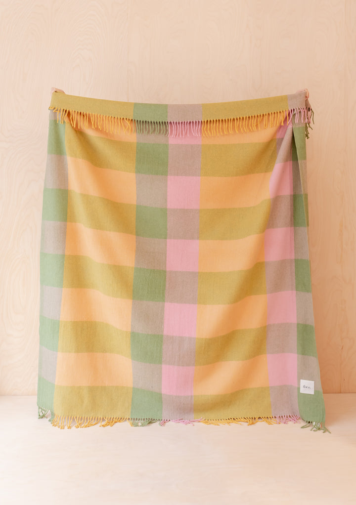 TBCo Recycled Wool Blanket in Green Bold Check hanging flat against pale wood with soft fringed edges visible
