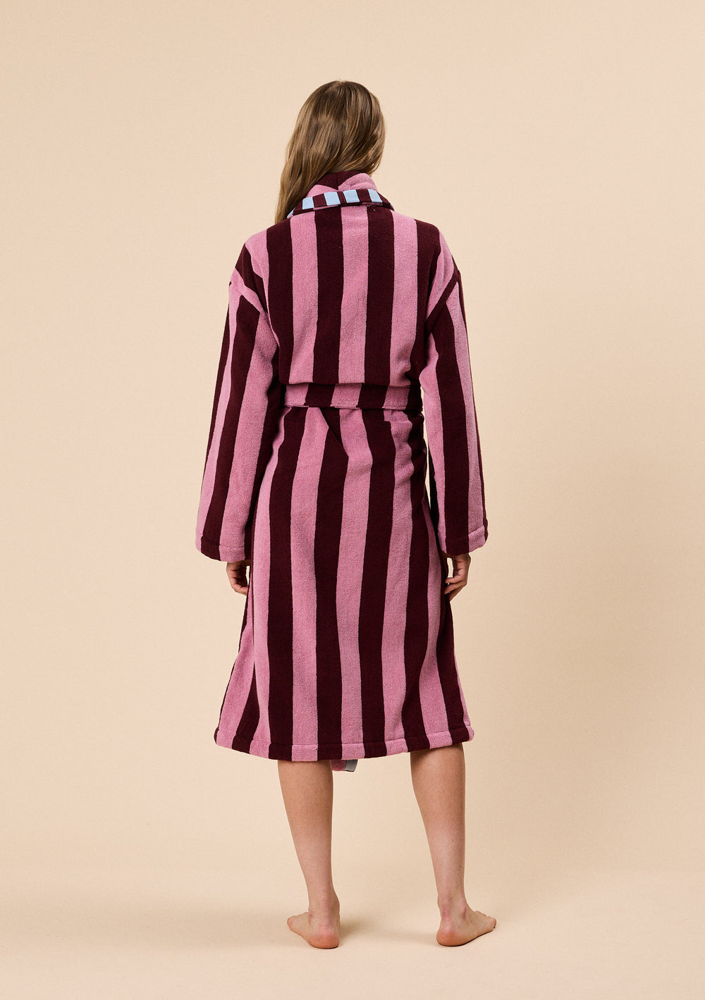 Back view of a model wearing TBCo Terry Cotton Bath Robe in Burgundy Stripe with wide vertical stripes and belt detail