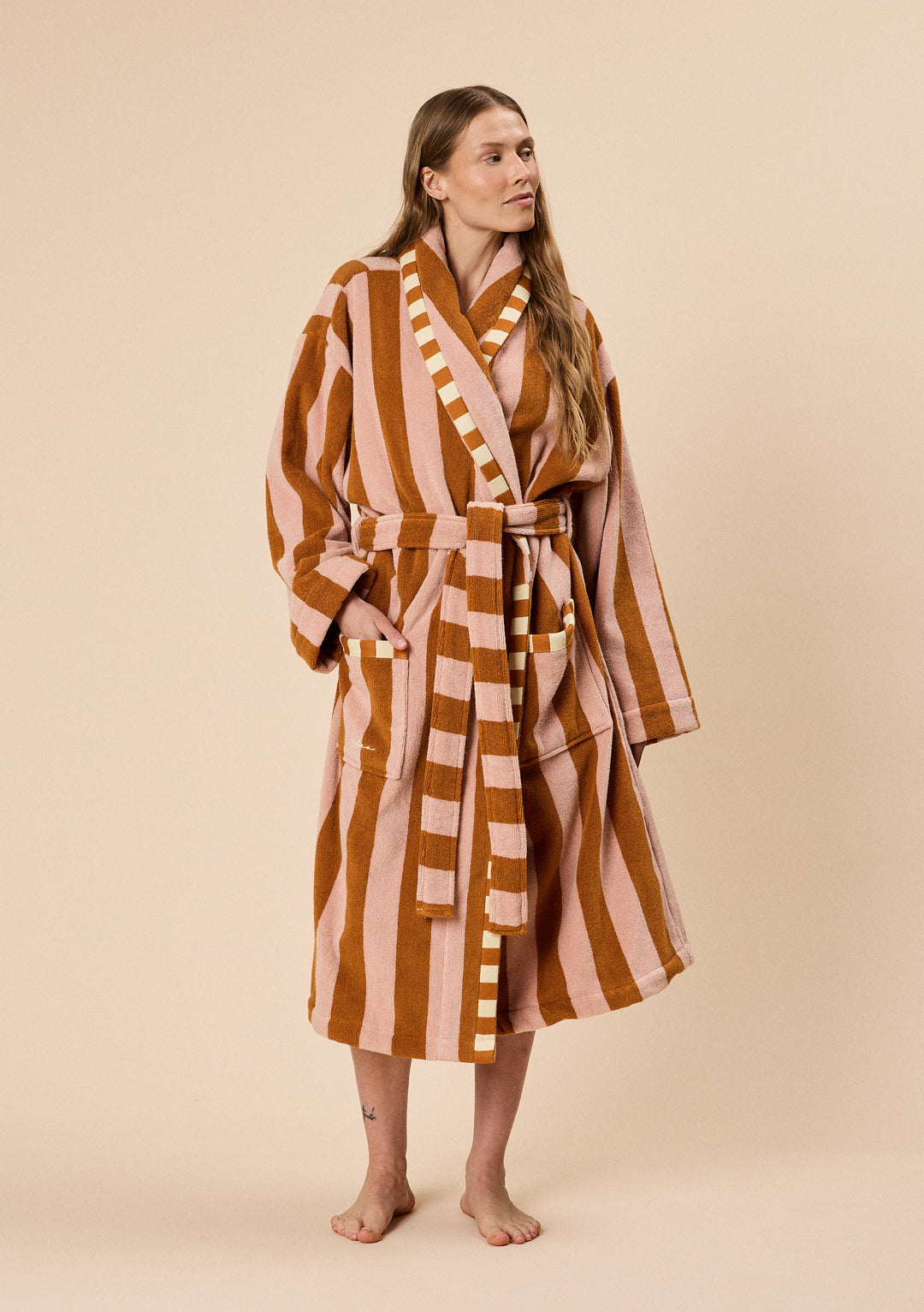 Model wearing TBCo Terry Cotton Bath Robe in Honeycomb Stripe with warm tones and striped belt tied at waist