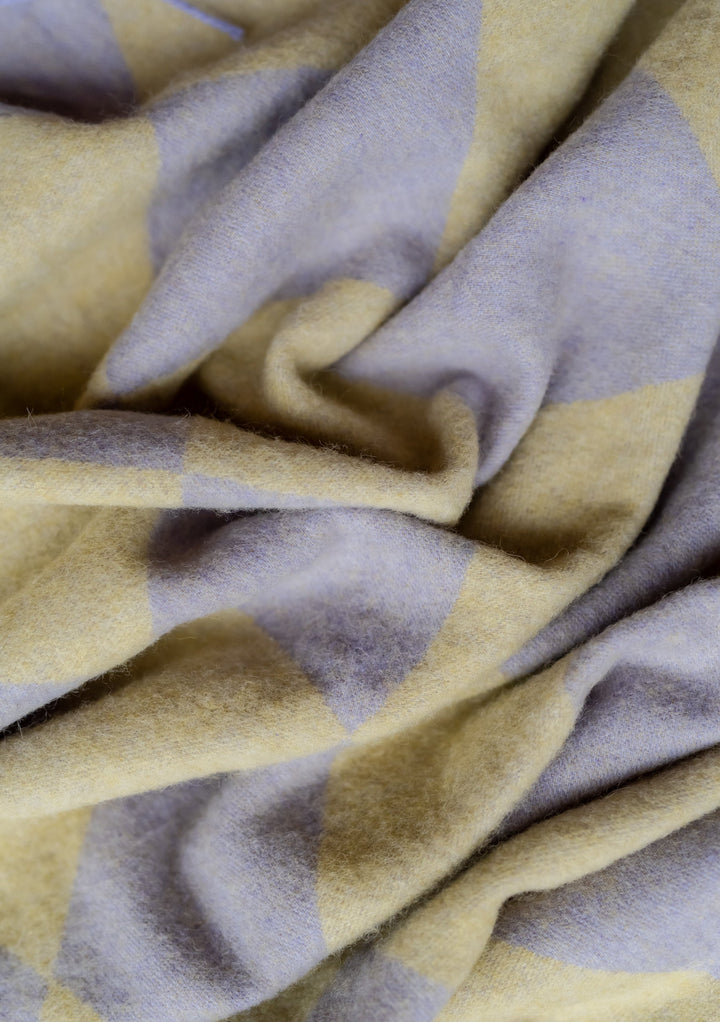 Close-up detail of TBCo Lambswool Oversized Scarf in Organic Jacquard showing lavender and green checkerboard pattern texture
