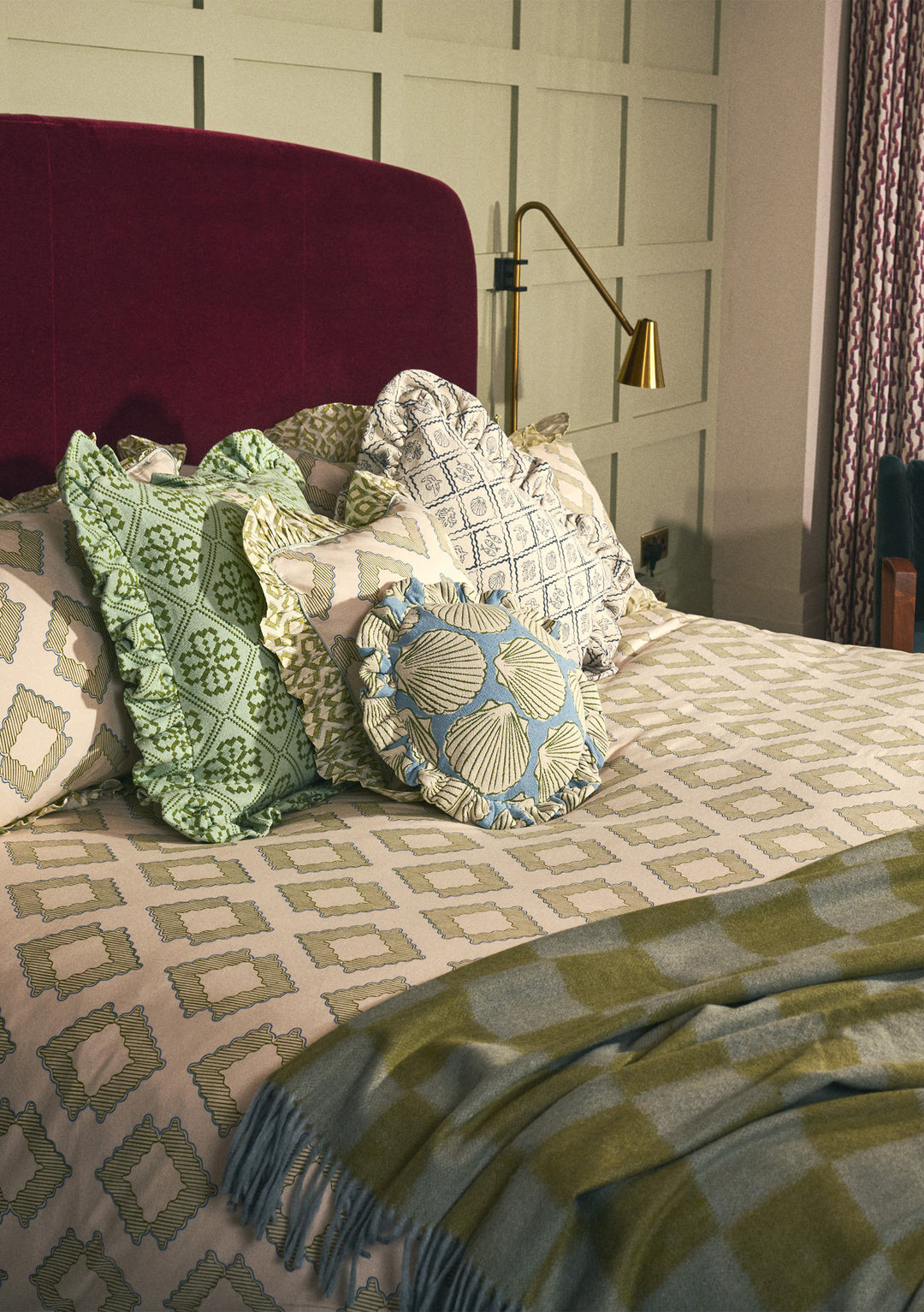 Portrait view of TBCo Mix & Match Blanket with Cushion Set styled on bed with patterned cushions and olive blanket