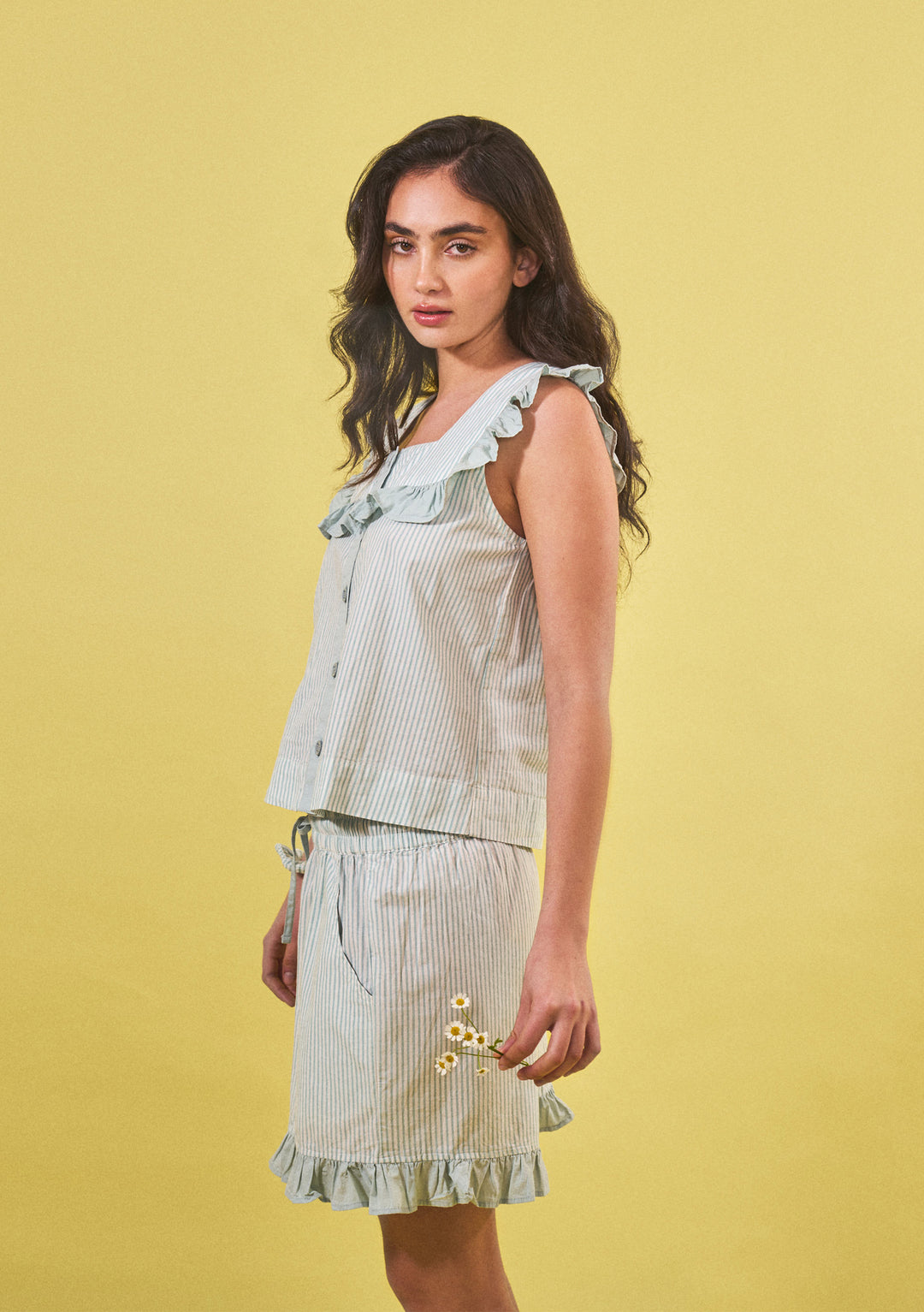 Portrait of a woman wearing TBCo Sleepwear Set with ruffled edges against a yellow background gallery position 1