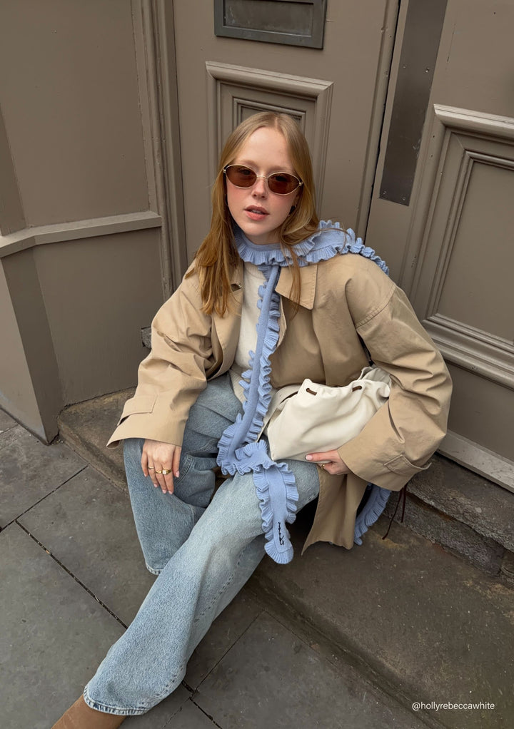 Woman seated outdoors wearing TBCo Merino Wool Skinny Scarf in Blue Ruffle with natural fibres, designed to make an impact