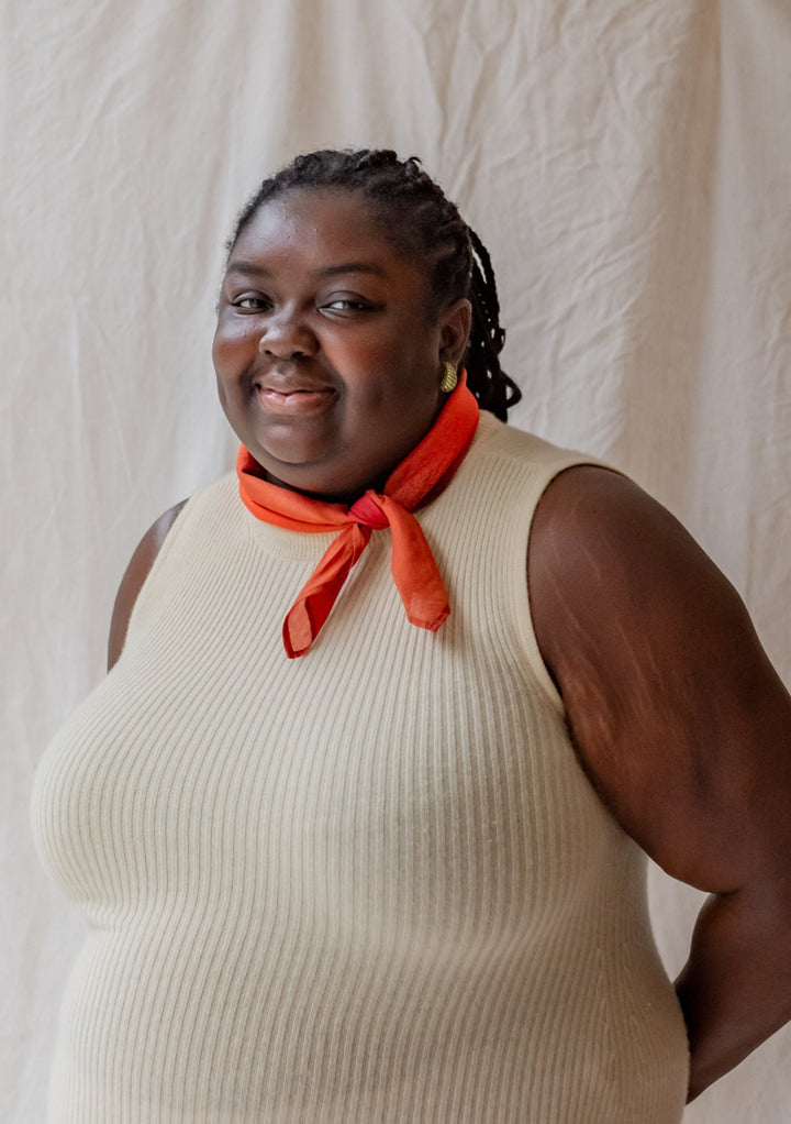 Smiling woman wearing a red Sample Sale TBCo x Abisola Omole Hues Cotton Scarf with a cream sleeveless top