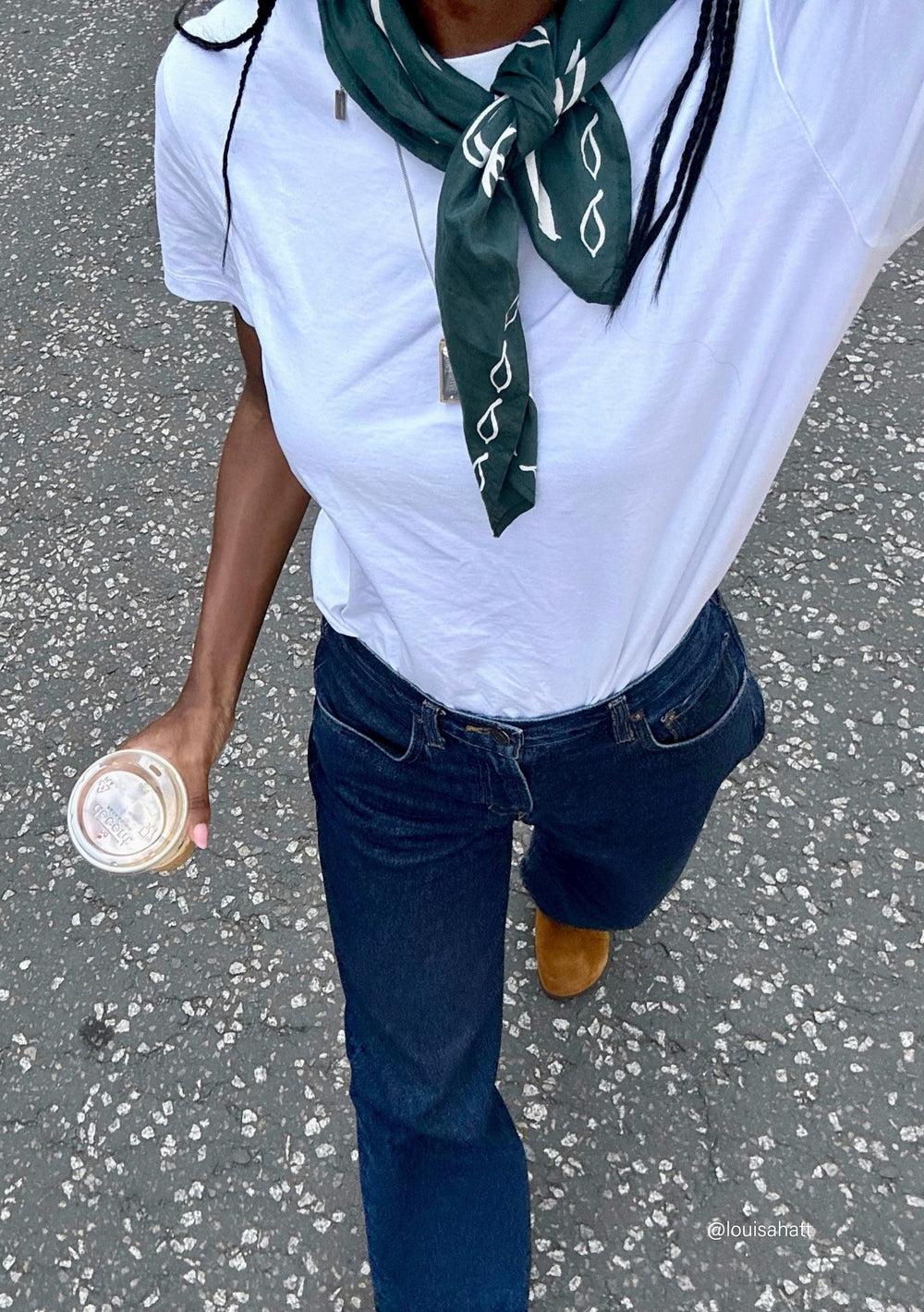 Person wearing The Artist Series TBCo x Simone Brewster Cotton Scarf, green patterned, around neck, with tan suede ankle boots, holding iced coffee.